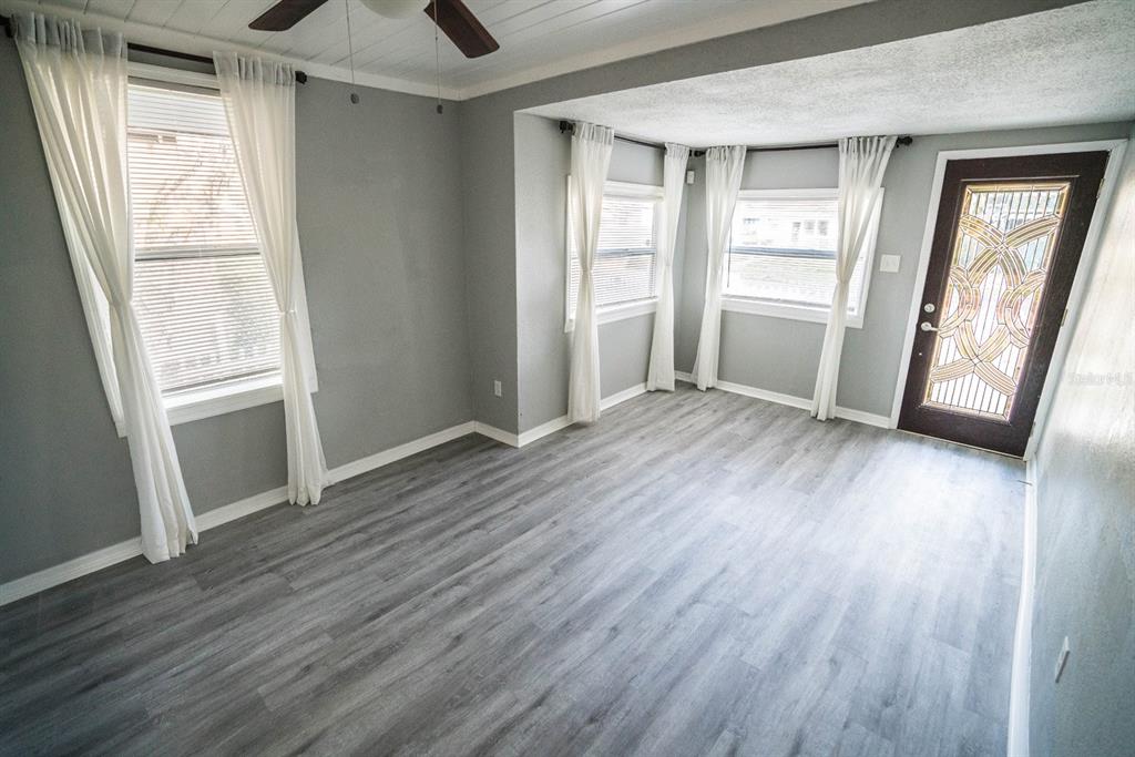 A room with gray walls, wood-look flooring, white curtains, and a decorative glass door — 2625 4TH AVENUE S, ST PETERSBURG, FL