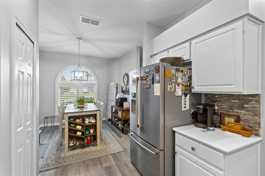 A dining room features a wooden table, chairs, a wall-mounted shelf, and an arched window — 146 CLUB VILLAS LANE, KISSIMMEE, FL