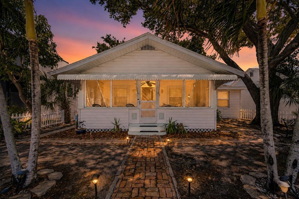 A white cottage with a screened-in front porch and a brick walkway under palm trees — 3829 2ND AVENUE N, ST PETERSBURG, FL
