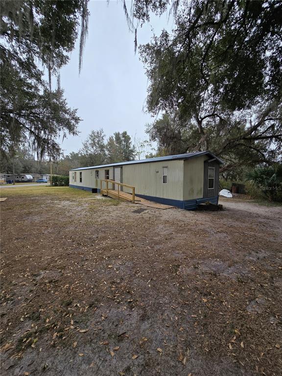 A single-story mobile home with a wooden wheelchair ramp sits on a dirt lot — 20 SW 3RD STREET, WEBSTER, FL