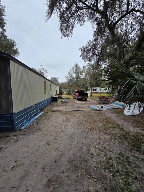 A side view of a mobile home exterior with a dirt yard and parked truck — 20 SW 3RD STREET, WEBSTER, FL
