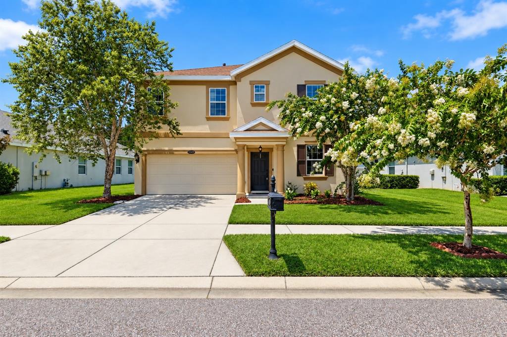 A two-story suburban house with a beige exterior, a two-car garage, and a front lawn — 21439 SOUTHERN CHARM DRIVE, LAND O LAKES, FL