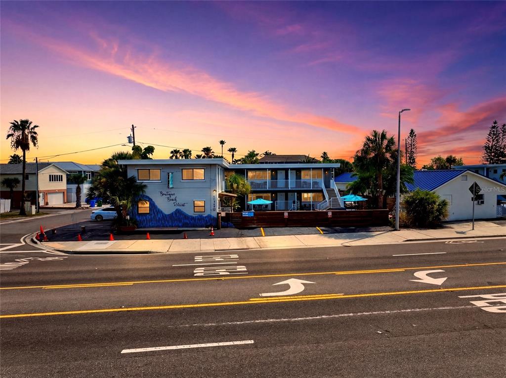 A two-story boutique beach retreat hotel building sits along a road at sunset — 11965 GULF BOULEVARD, ST PETERSBURG, FL