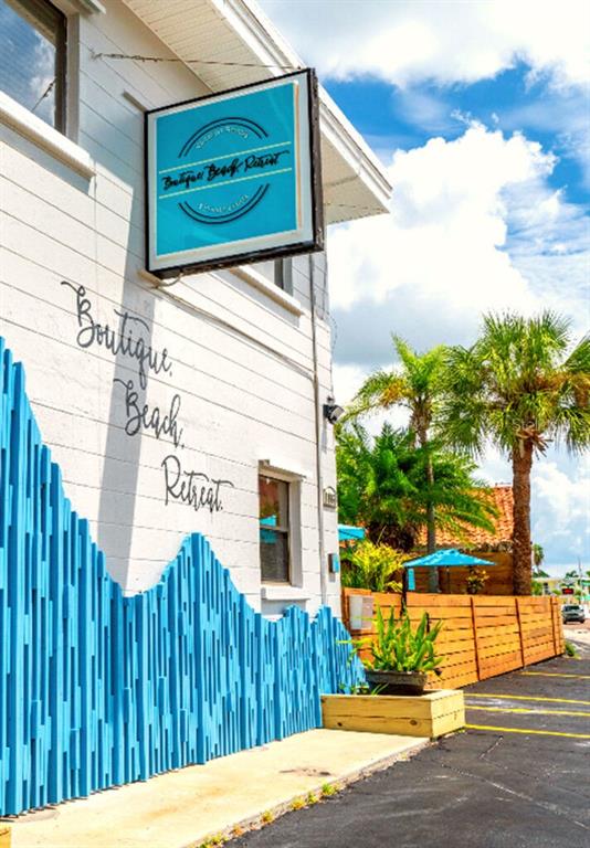 The exterior of a white building features a blue wave-patterned fence and a hanging sign — 11965 GULF BOULEVARD, ST PETERSBURG, FL