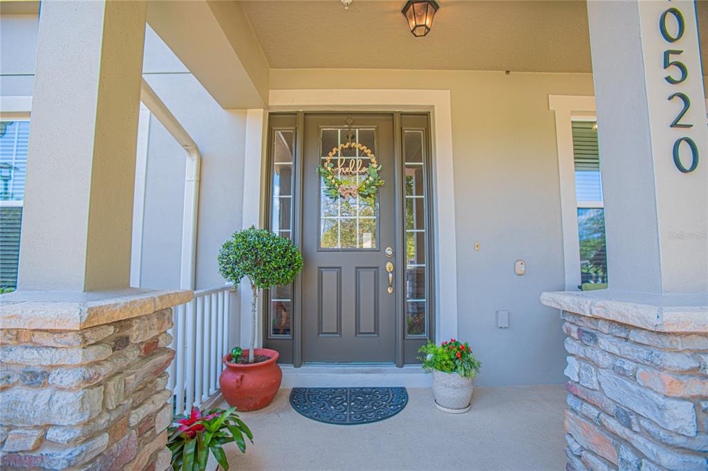 A front porch features a dark brown door with a wreath and stone-clad columns — 10520 BURROWS STREET, ORLANDO, FL