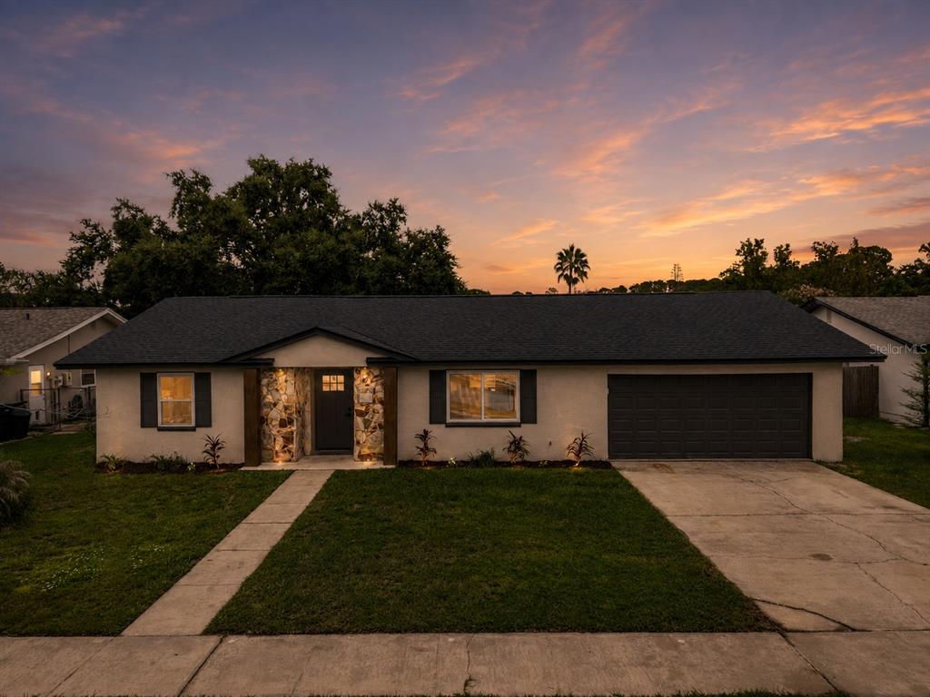 An aerial view of a single-story house with a stone entryway and a sunset sky — 8624 BAYLOR CIRCLE, ORLANDO, FL