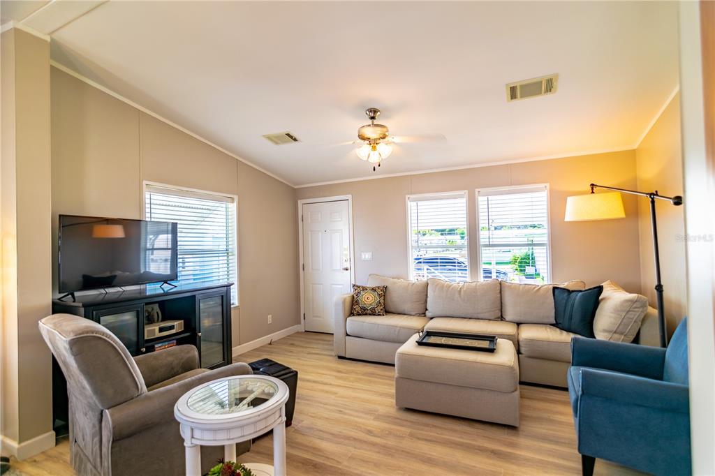 A living room features light wood-look flooring, a beige sectional sofa, and a television console — 8320 RIVERSIDE DRIVE UNIT 51B, PUNTA GORDA, FL