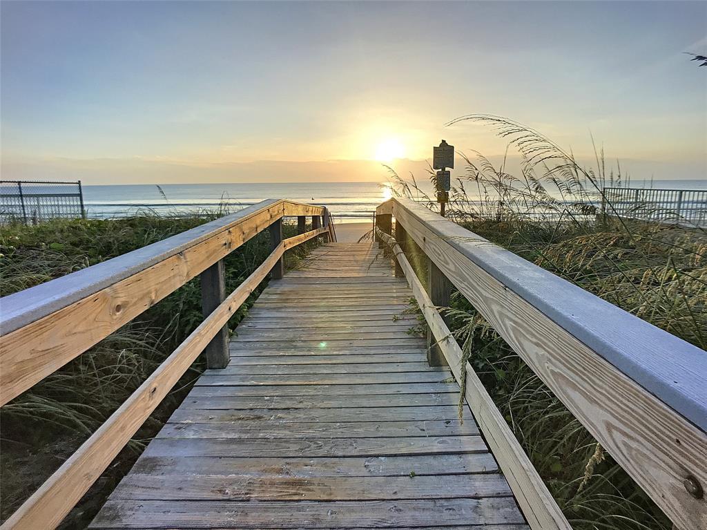 A wooden boardwalk leads through sand dunes toward the ocean at sunrise — 4148 MICHIGAN AVENUE, NEW SMYRNA BEACH, FL