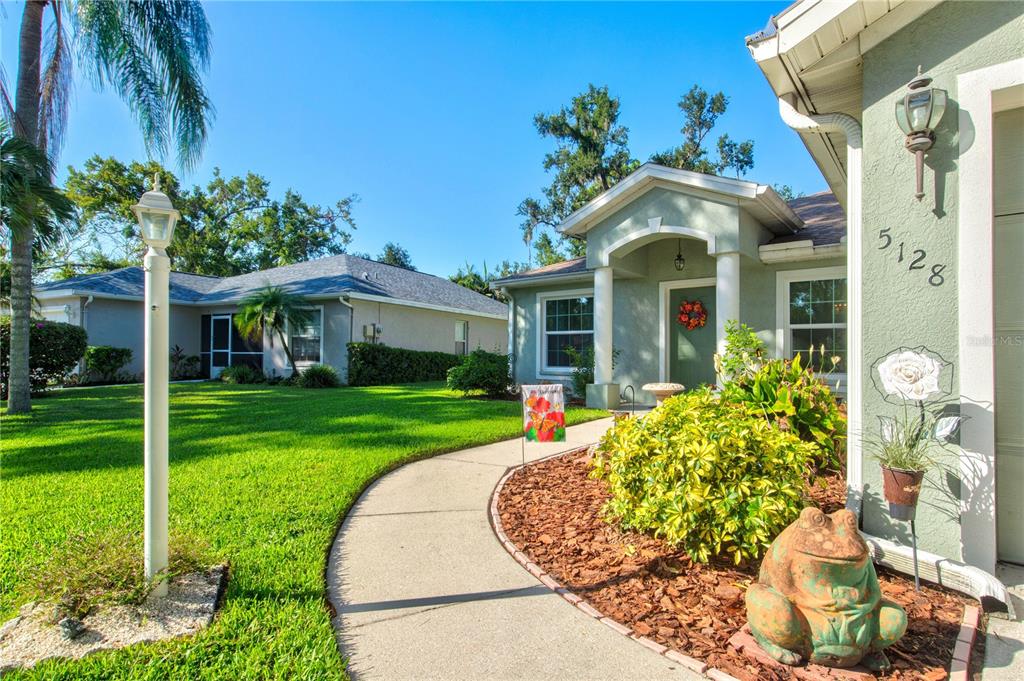 A single-story light green house with a two-car garage and a front walkway — 5128 18TH LANE E, BRADENTON, FL