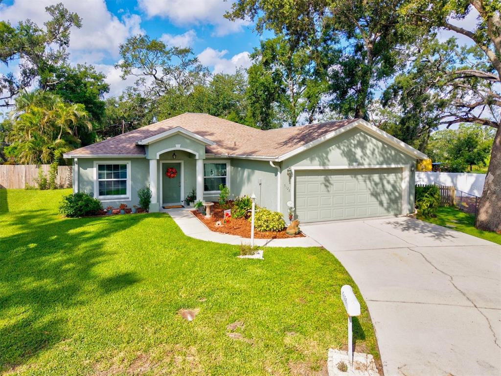 A light green house with a curved walkway, a front lawn, and a frog statue — 5128 18TH LANE E, BRADENTON, FL