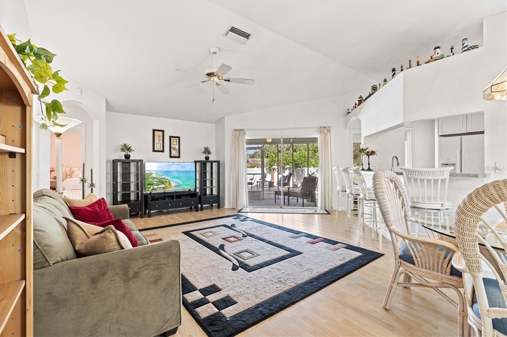 A living room features a sofa, area rug, television, and a view of a patio — 5128 18TH LANE E, BRADENTON, FL