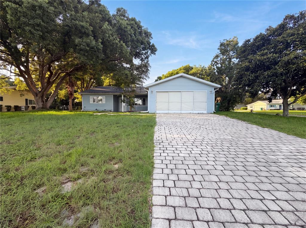 A light blue single-story house features a paved driveway and a large front yard — 10337 SE 176TH STREET, SUMMERFIELD, FL