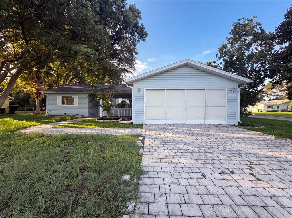 A light blue single-story house features a paved driveway and a large attached garage — 10337 SE 176TH STREET, SUMMERFIELD, FL