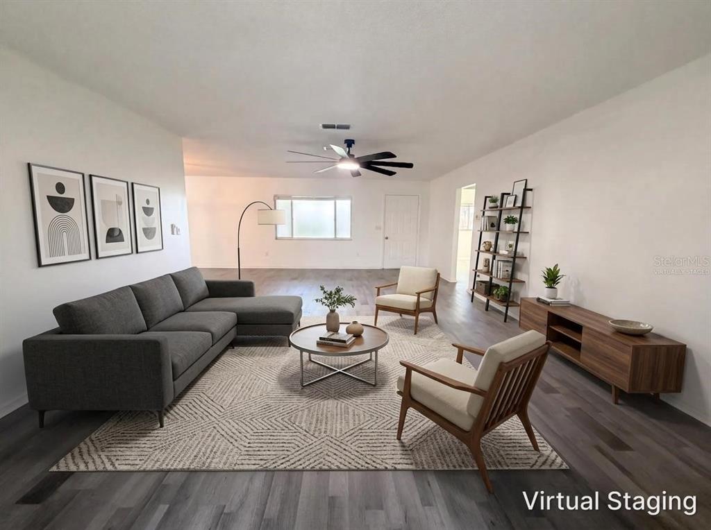 A virtually staged living room features a gray sectional, two armchairs, and wood-look flooring — 10337 SE 176TH STREET, SUMMERFIELD, FL