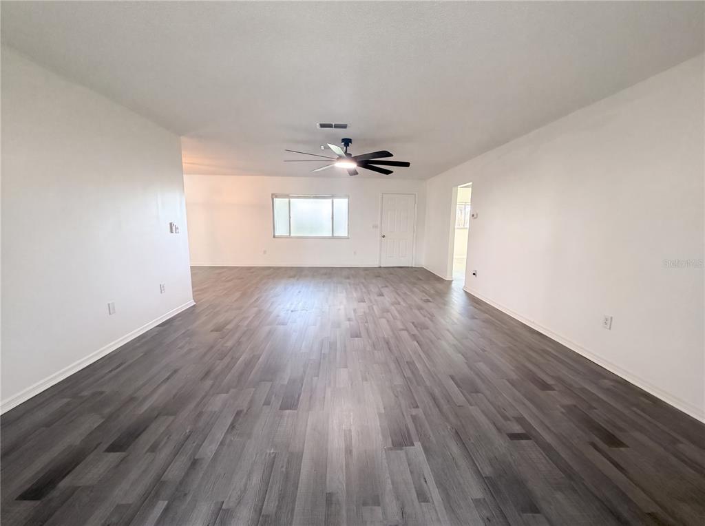 An empty room with white walls, gray wood-look flooring, and a ceiling fan — 10337 SE 176TH STREET, SUMMERFIELD, FL