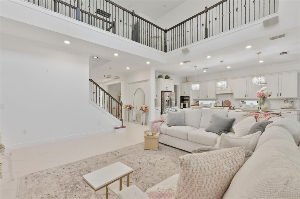 A spacious living room with a high ceiling, white walls, and an open kitchen area — 11481 OWASEE TRAILS PLACE, RIVERVIEW, FL