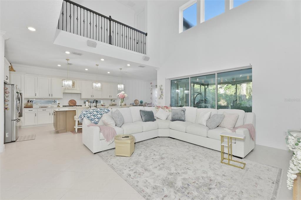 A bright, open-concept living room features a large white sectional sofa and a high ceiling — 11481 OWASEE TRAILS PLACE, RIVERVIEW, FL