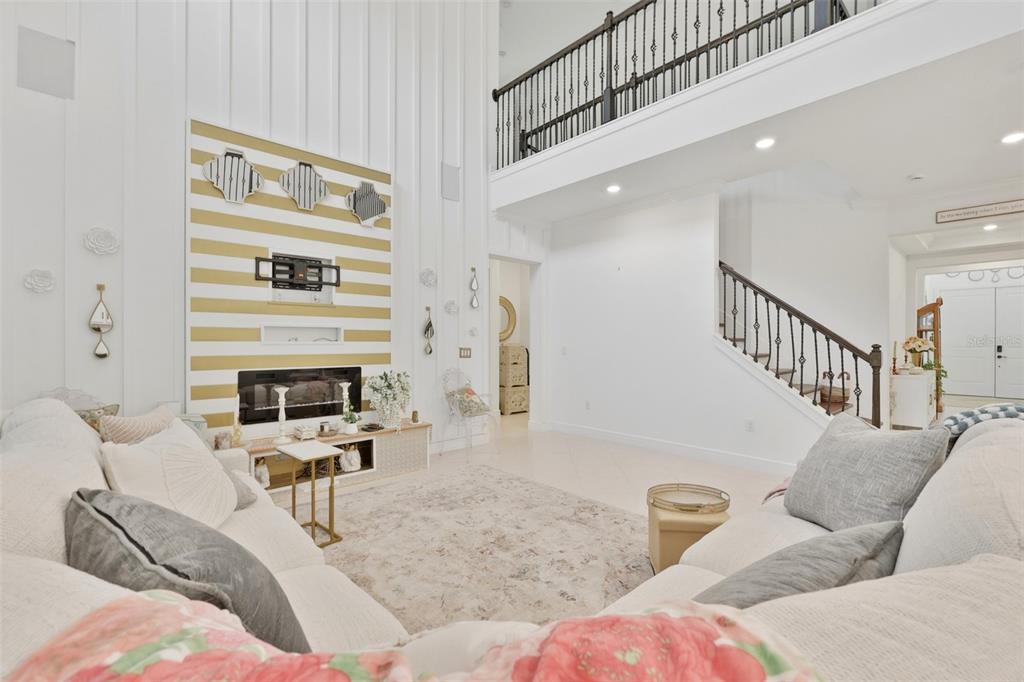 A living room features a striped accent wall with a fireplace and a staircase nearby — 11481 OWASEE TRAILS PLACE, RIVERVIEW, FL