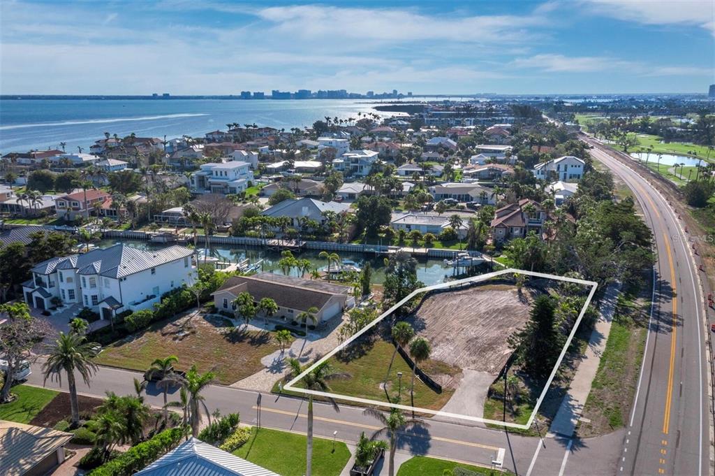An aerial view shows a vacant, trapezoidal lot outlined in white next to a paved road — 500 OUTRIGGER LANE, LONGBOAT KEY, FL