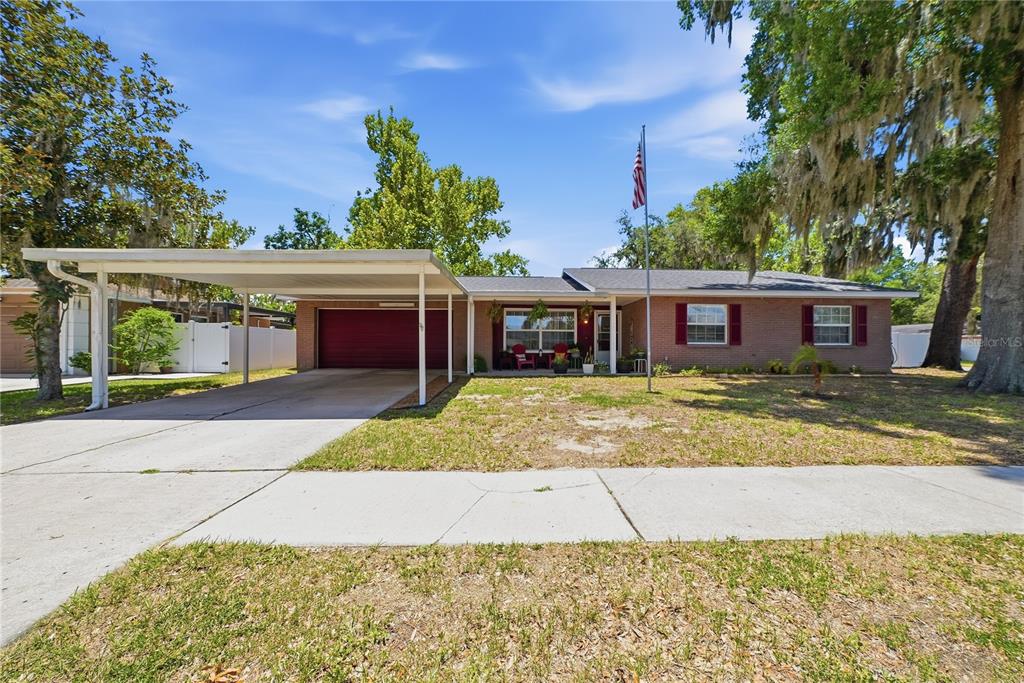 A single-story brick house features a carport, a front porch, and a flag pole — 3801 UPLAND PLACE, VALRICO, FL
