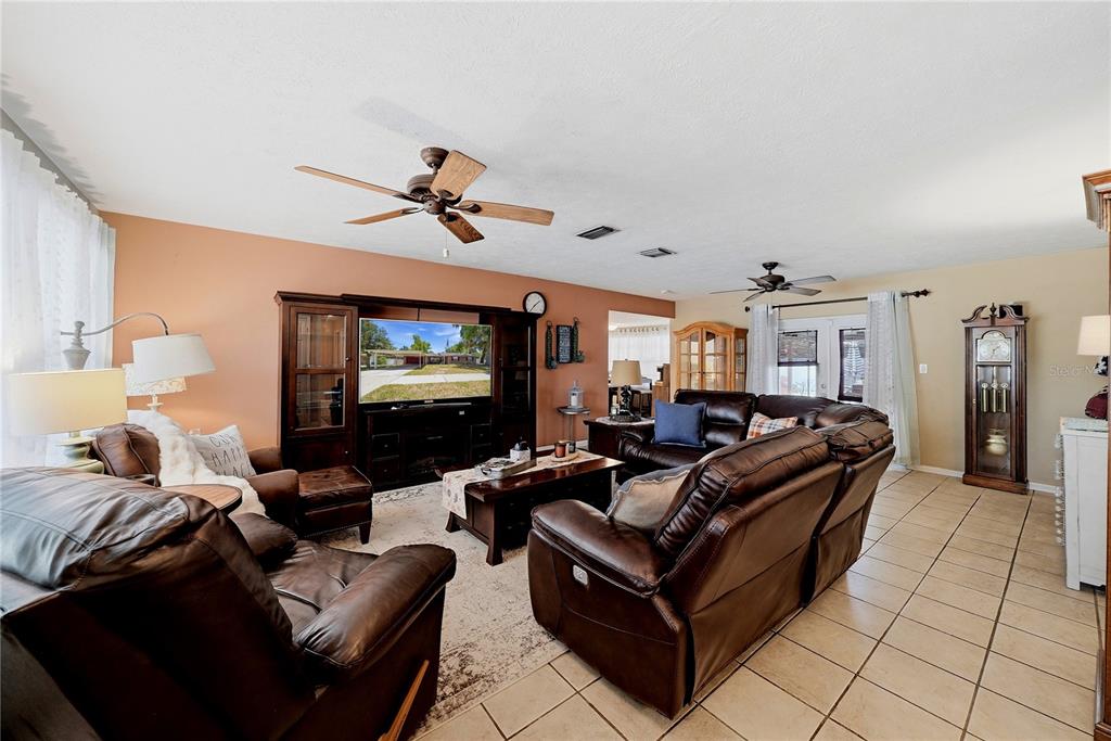 A living room features brown leather furniture, a large entertainment center, and tile flooring — 3801 UPLAND PLACE, VALRICO, FL