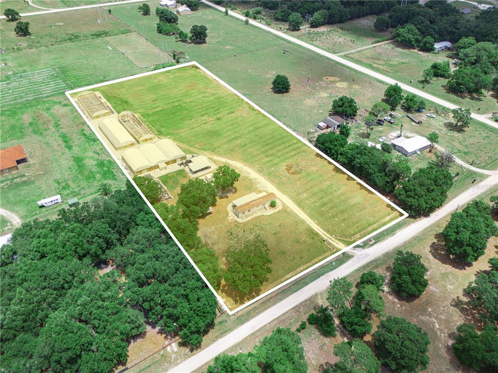 An aerial view shows a rural property with a house, several greenhouses, and fenced pastures — 612 MORGAN ROAD, WINTER HAVEN, FL