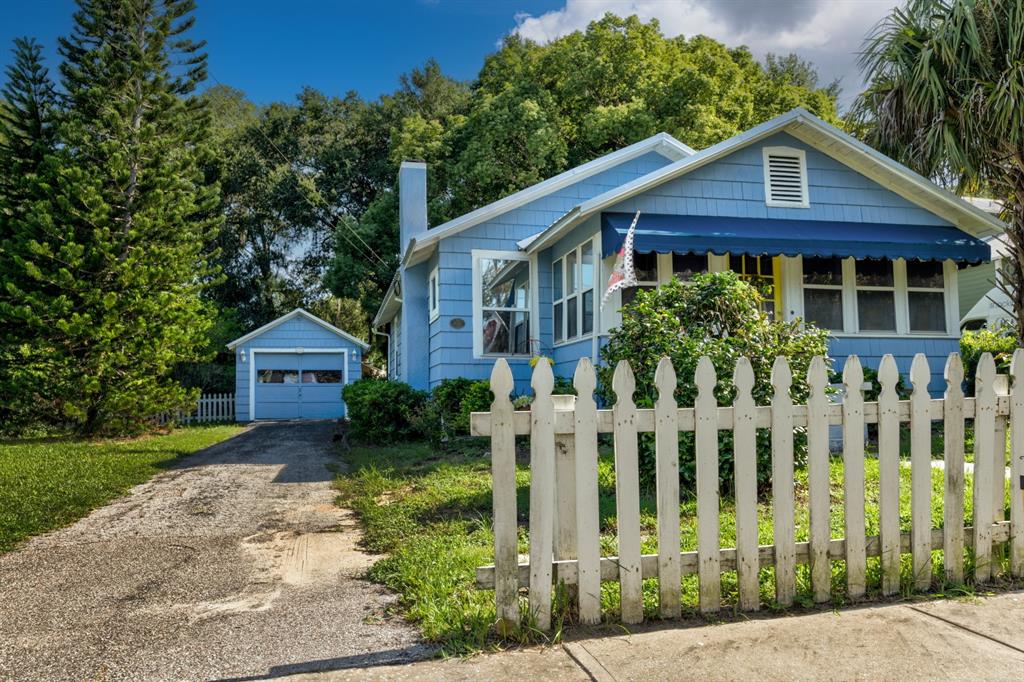 A blue house with a white picket fence, a driveway, and a detached garage — 401 E 9TH AVENUE, MOUNT DORA, FL