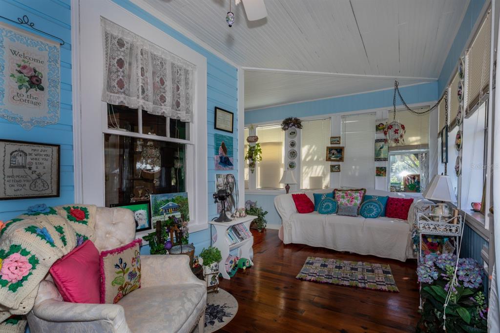 A sunroom with blue walls, wood floors, a white sofa, and an armchair — 401 E 9TH AVENUE, MOUNT DORA, FL