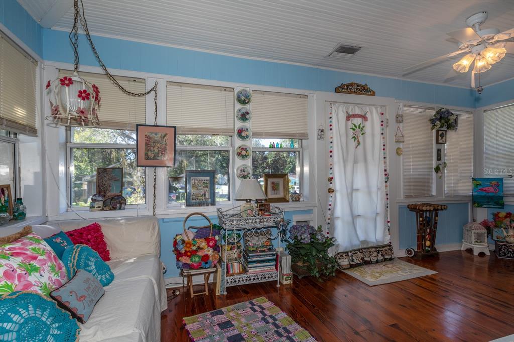 A sunroom with blue walls, wood floors, a white ceiling, and multiple windows with blinds — 401 E 9TH AVENUE, MOUNT DORA, FL