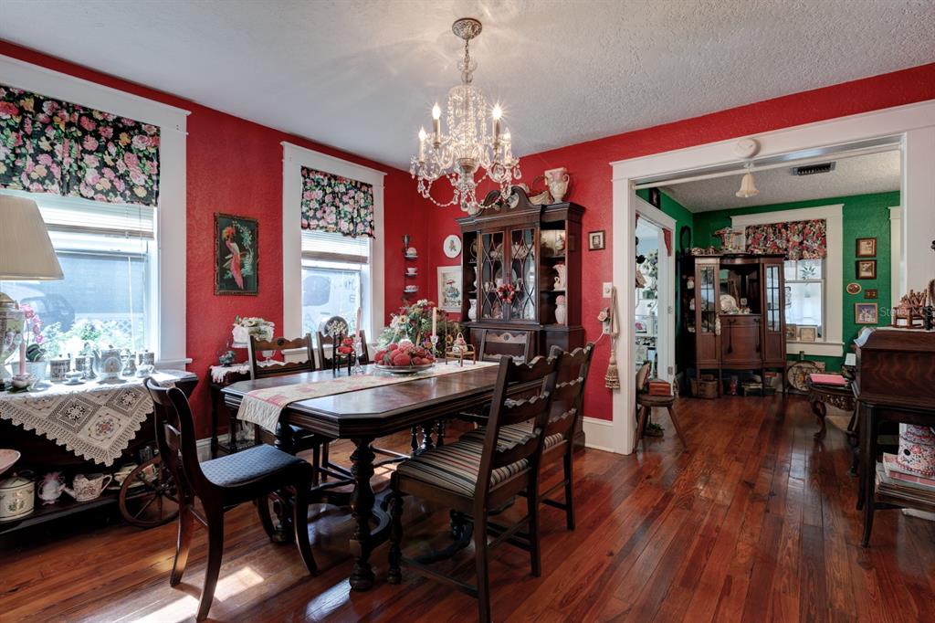 A dining room with red walls, a crystal chandelier, wooden furniture, and hardwood floors — 401 E 9TH AVENUE, MOUNT DORA, FL