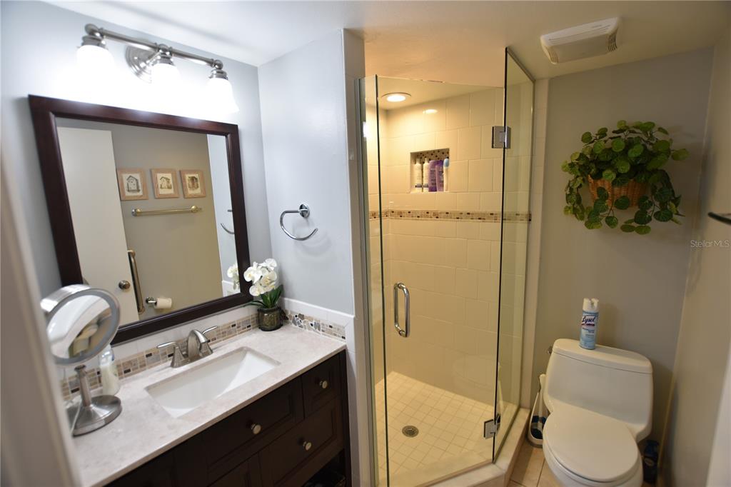 A kitchen features white cabinets, a white stove, a microwave, and speckled granite countertops — 4626 RINGWOOD MEADOW UNIT 25, SARASOTA, FL