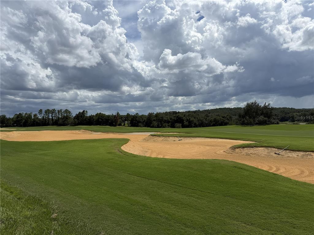 A view of a golf course fairway featuring large sand bunkers under a cloudy sky — 15950 VETTA DRIVE, MONTVERDE, FL