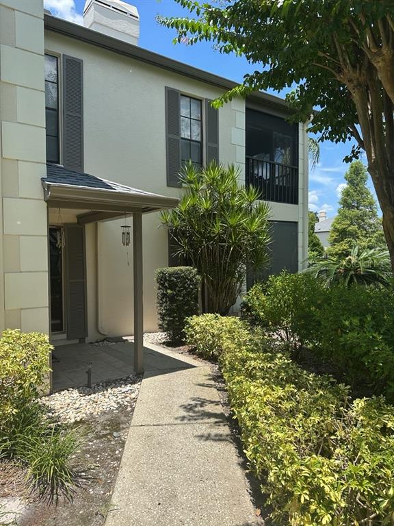 A concrete walkway leads to the covered entrance of a two-story stucco townhouse — 13046 VILLAGE CHASE CIRCLE UNIT 13046, TAMPA, FL