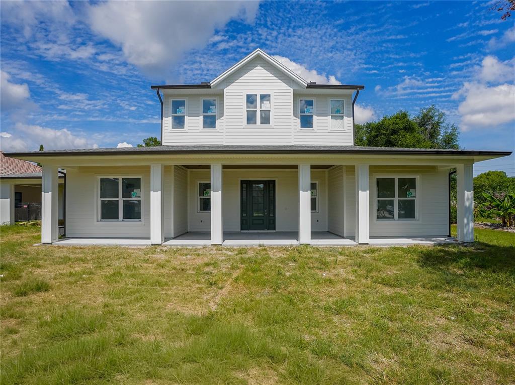A covered front porch features white horizontal siding, a green front door, and recessed lighting — 1122 DINGENS AVENUE, GOTHA, FL