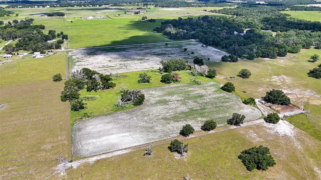 An aerial view shows a large, flat, rural plot of land with patches of trees — CR 665, ONA, FL