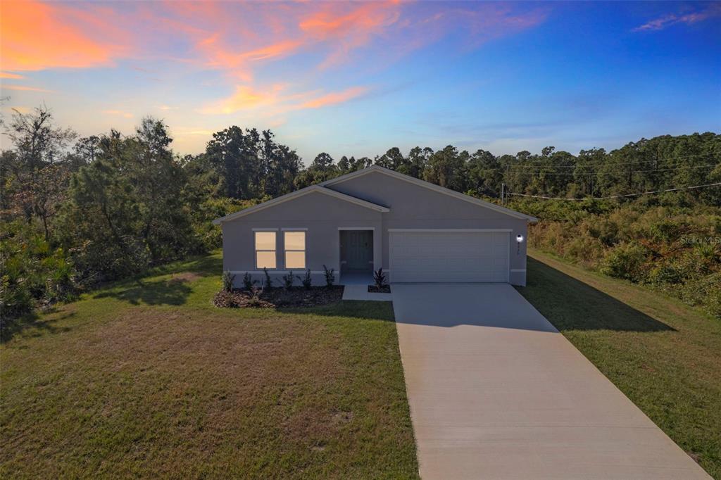 A single-story house with a gray exterior, a two-car garage, and a concrete driveway — 8614 GRANADA BOULEVARD, SEBRING, FL
