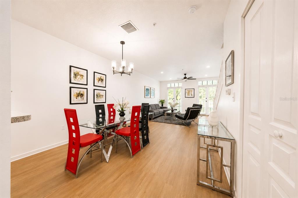 A dining area with red chairs leads into a living room with glass doors — 660 CELEBRATION AVENUE UNIT 240, KISSIMMEE, FL