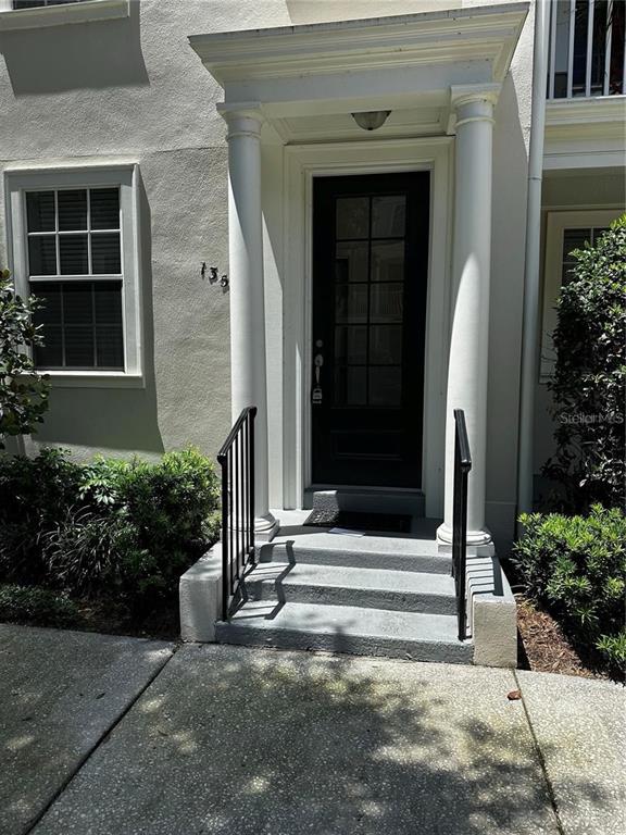 A front entrance features a dark door with glass panes, white columns, and concrete steps — 1350 CHATFIELD PLACE, ORLANDO, FL