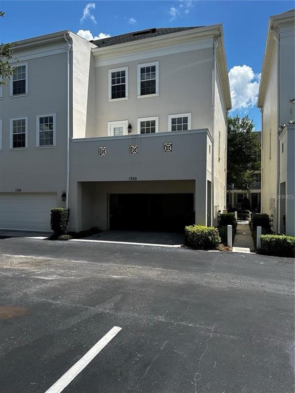 A three-story townhouse exterior features a ground-level garage and a second-story balcony — 1350 CHATFIELD PLACE, ORLANDO, FL