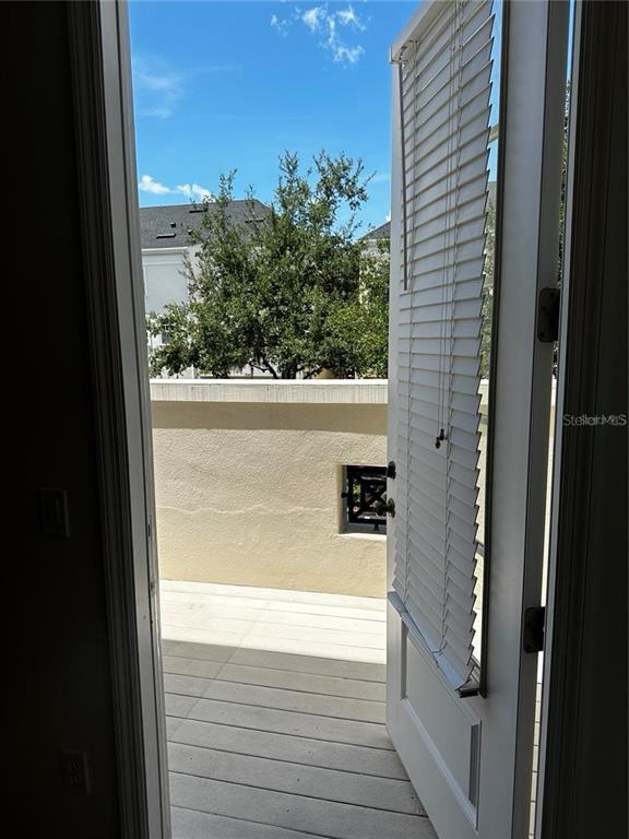 An open door with white blinds leads to a balcony with a tan wall — 1350 CHATFIELD PLACE, ORLANDO, FL