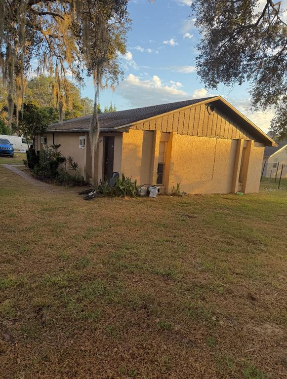A side view of a single-story stucco house with a dark shingled roof and landscaping — 3108 - 3110 - 3112 - 3114 HOLLY STREET, LAKE WALES, FL