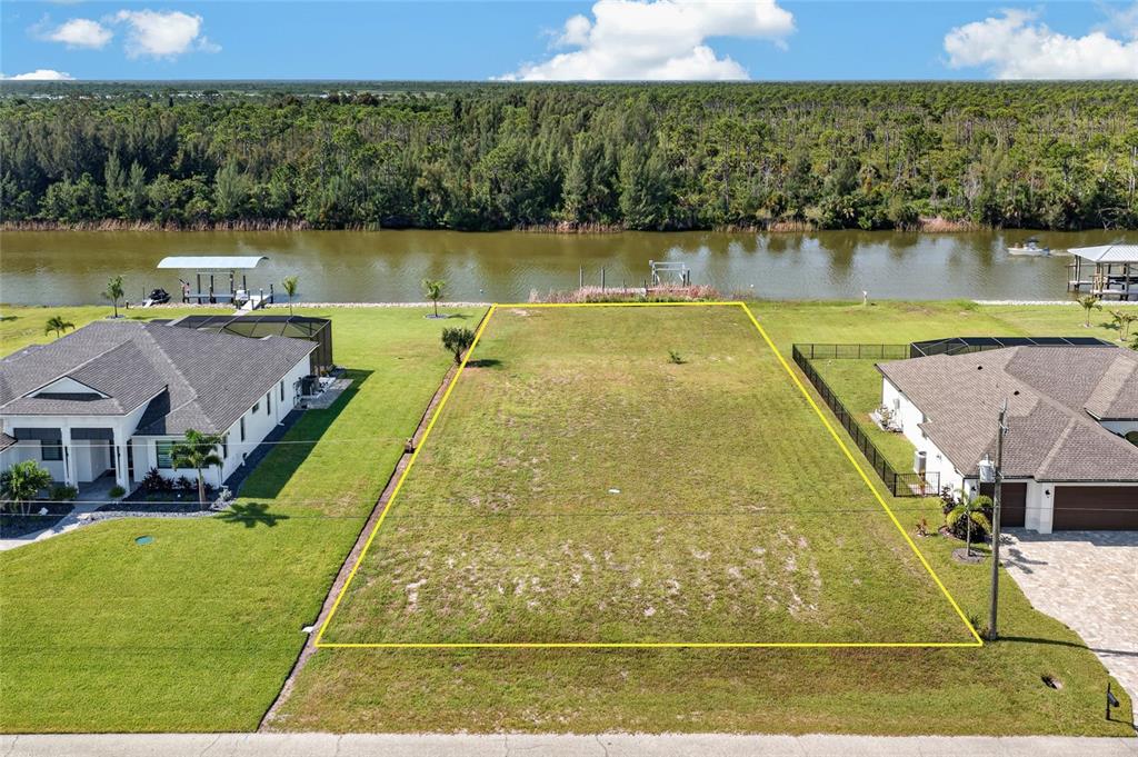 An aerial view shows a vacant waterfront lot situated between two residential houses — 16652 LIGGETT CIRCLE, PORT CHARLOTTE, FL