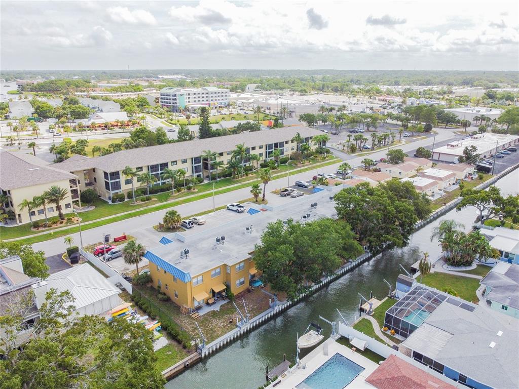 An aerial view shows a yellow apartment building next to a canal with a boat — 439 S PAULA DRIVE UNIT 202, DUNEDIN, FL