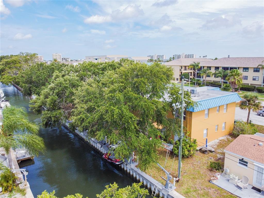 An aerial view shows a yellow building next to a canal with a boat lift — 439 S PAULA DRIVE UNIT 202, DUNEDIN, FL