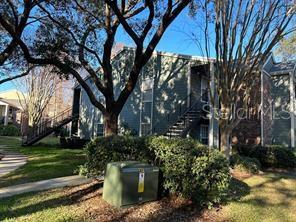 A multi-story apartment building with exterior staircases and large trees in the foreground — 2225 METROPOLITAN WAY UNIT 1218, ORLANDO, FL