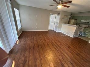 An open living area features wood-look flooring, a ceiling fan, and an adjacent kitchen counter — 2225 METROPOLITAN WAY UNIT 1218, ORLANDO, FL