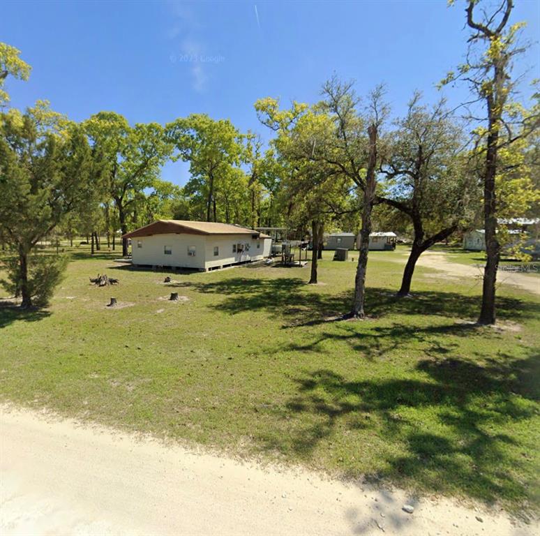 A single-story mobile home sits on a large, grassy lot with scattered trees — 2699 LIVE OAK ROAD, PERRY, FL