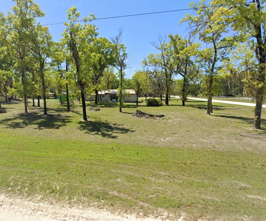 A single-story house sits on a large, grassy lot filled with many mature trees — 2699 LIVE OAK ROAD, PERRY, FL