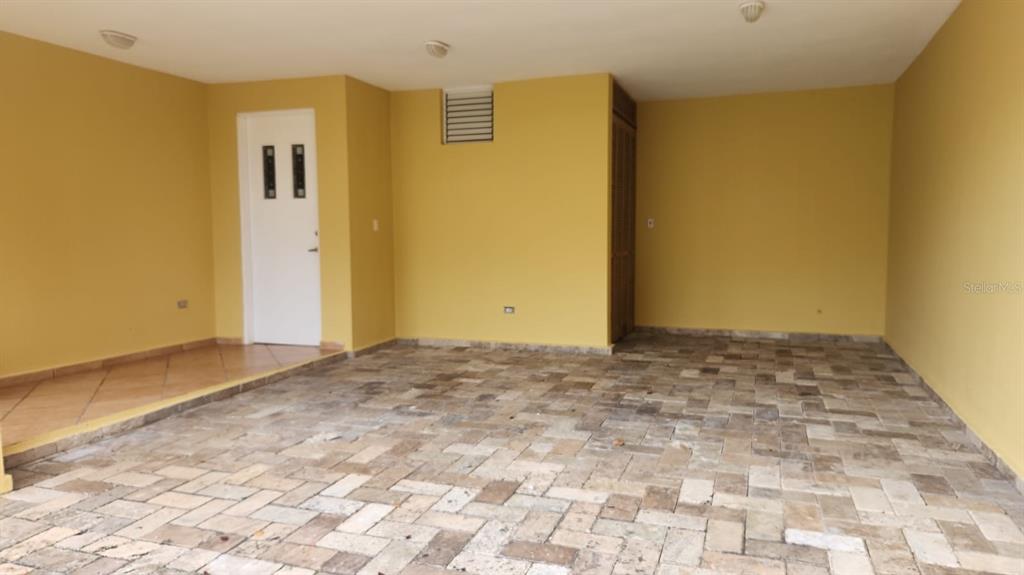 A covered carport with yellow walls, a white door, and a stone paver floor — Harbour Drive Street PLAZA DEL PUERTO @ PALMAS DEL MAR DRIVE NE UNIT A-9, HUMACAO, PR