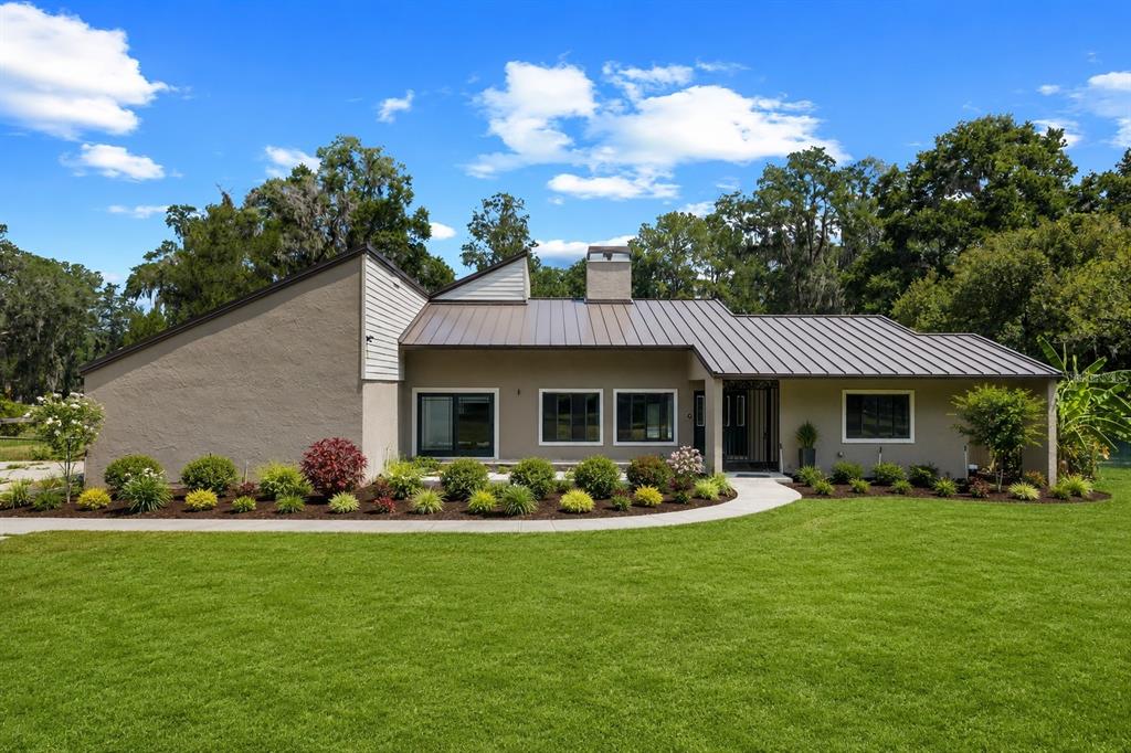 A single-story house with a metal roof and tan stucco exterior sits behind a lawn — 3261 SE 41ST PLACE, OCALA, FL